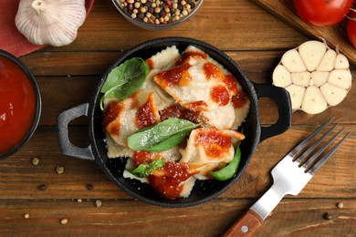 Photo of Tasty ravioli with tomato sauce served on wooden table, flat lay