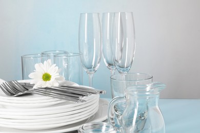 Photo of Set of clean dishes, glasses and cutlery on table, closeup