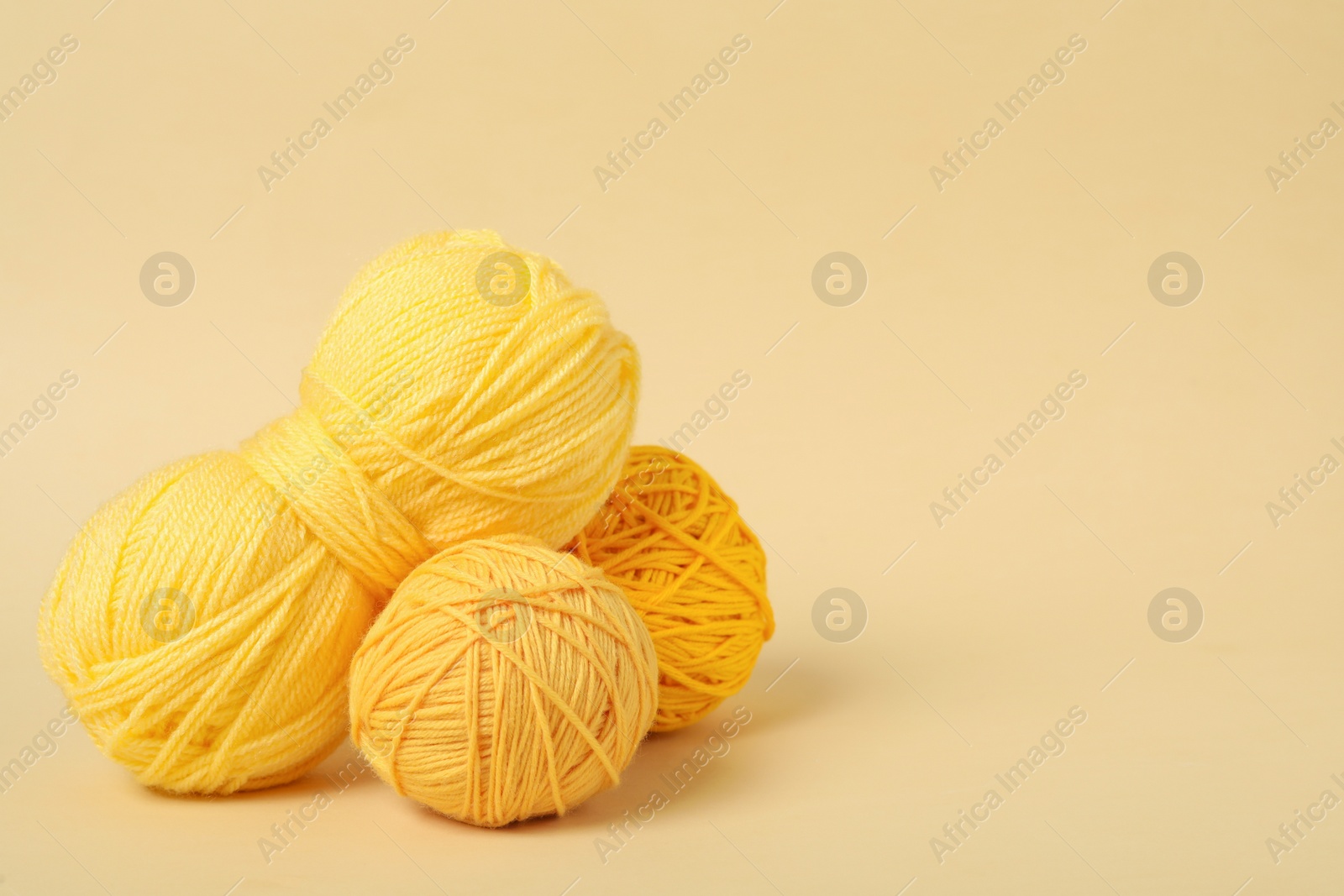 Photo of Soft yellow woolen yarns on beige background. Space for text