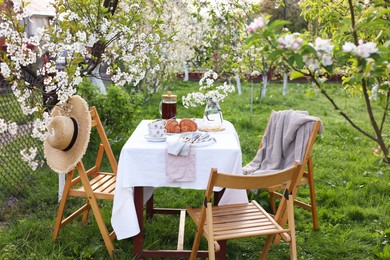 Photo of Stylish table setting with beautiful spring flowers, tea and croissants in garden