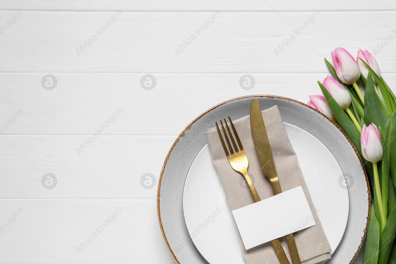 Photo of Stylish table setting with cutlery, paper card and tulips on white wooden background, flat lay. Space for text