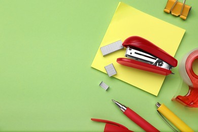 Flat lay composition with new stapler on green background, space for text