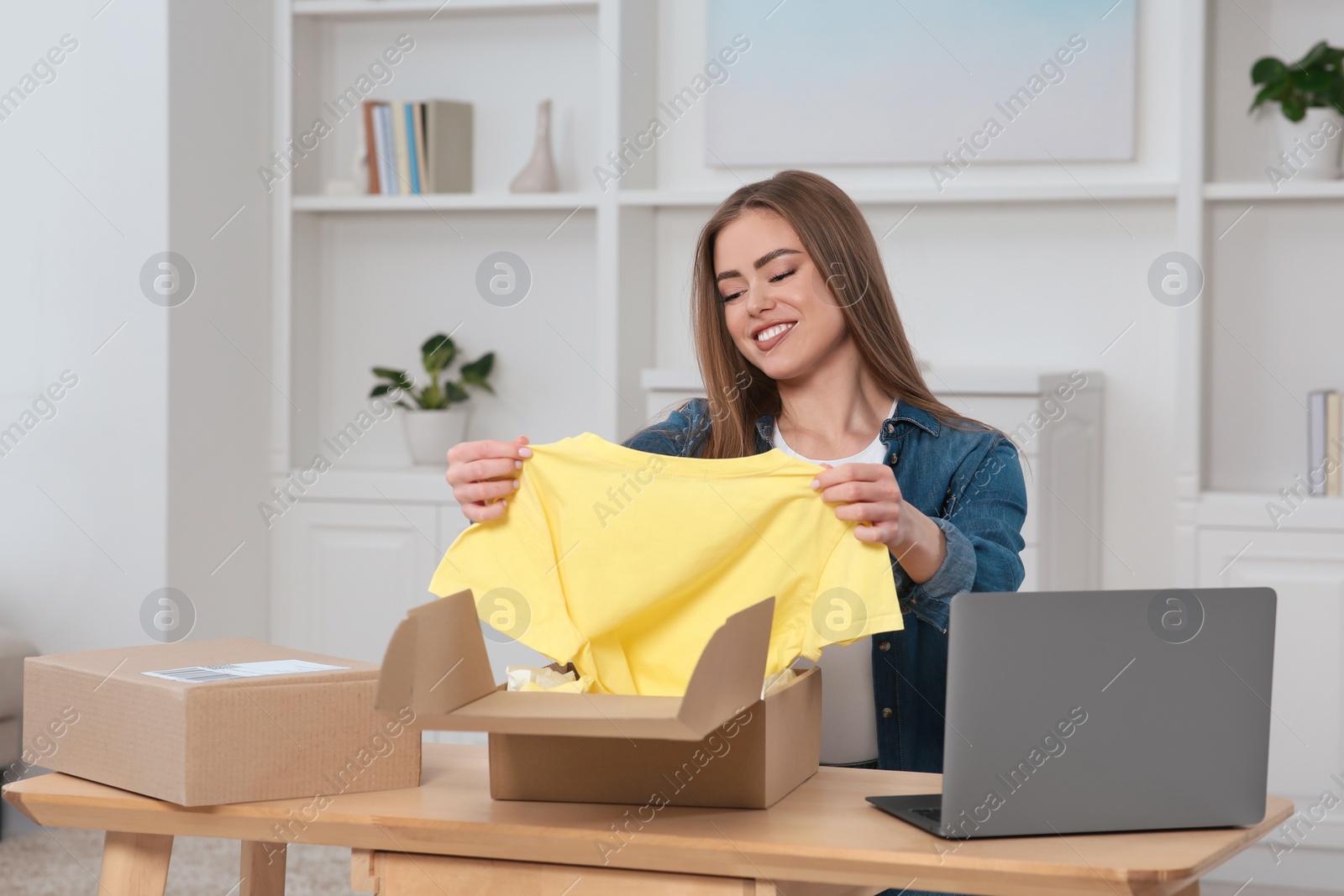 Photo of Happy woman unpacking parcel at home. Online store