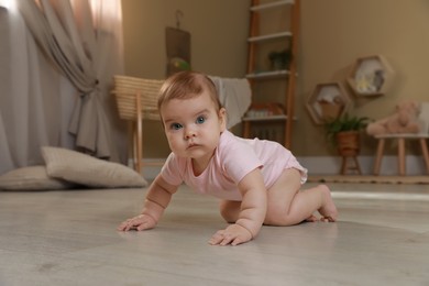 Cute baby crawling on floor at home