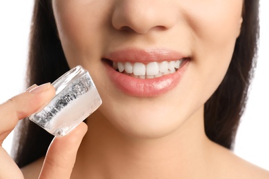 Young woman with ice cube on white background, closeup. Skin care