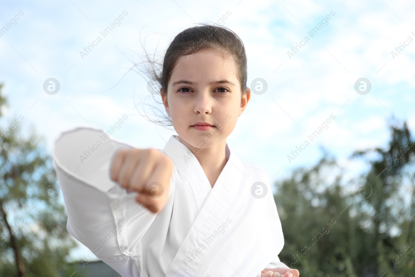 Photo of Cute little girl in kimono practicing karate outdoors