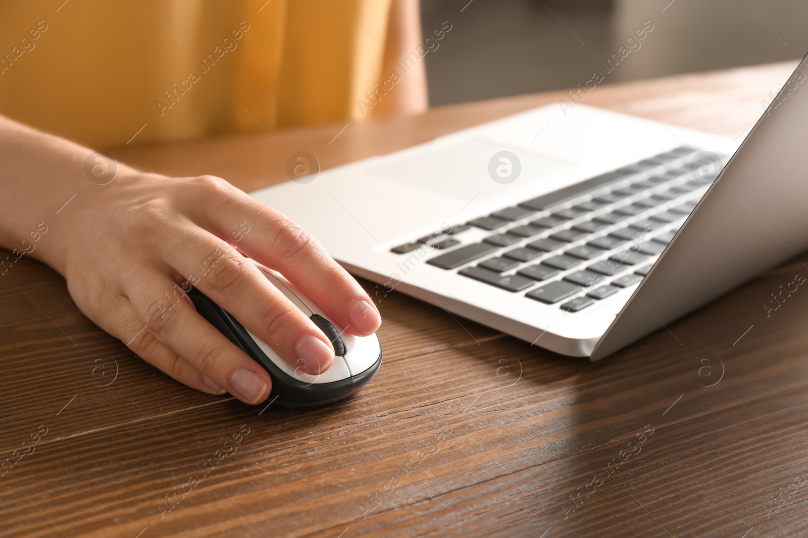 Photo of Woman using computer mouse with laptop at table, closeup