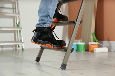 Photo of Person climbing ladder indoors, closeup on feet