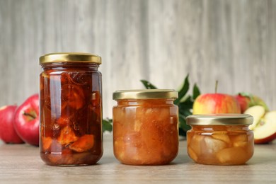 Tasty apple jam in glass jars on wooden table