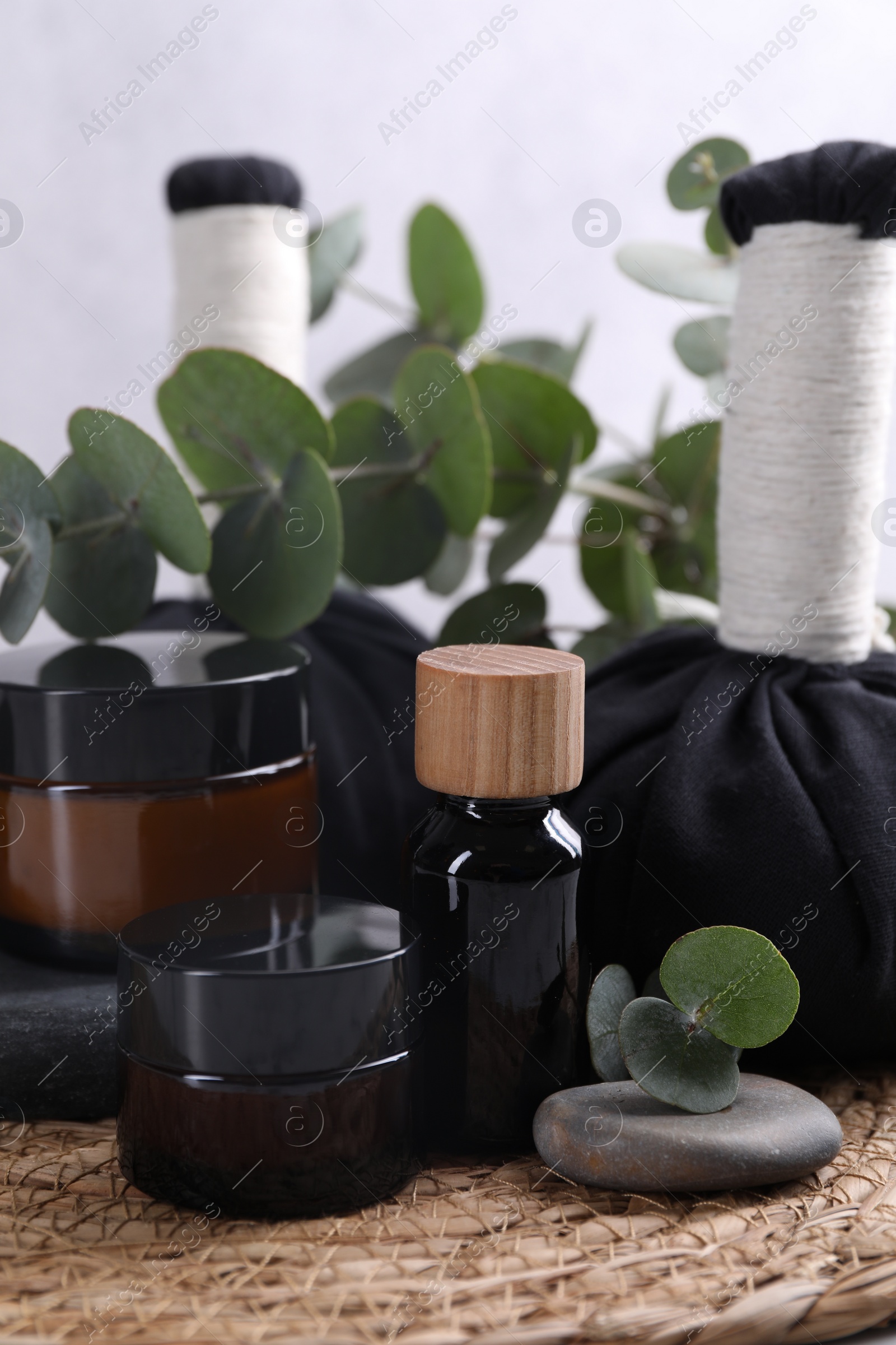 Photo of Spa composition with cosmetic products, herbal massage bags, stones and eucalyptus branches on table