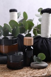 Photo of Spa composition with cosmetic products, herbal massage bags, stones and eucalyptus branches on table