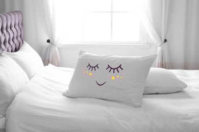 Image of Soft pillow with cute face on comfortable bed in room