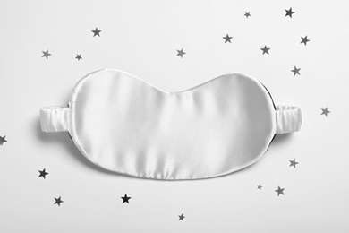 Photo of Sleeping mask and glitter on white background, top view. Bedtime accessory
