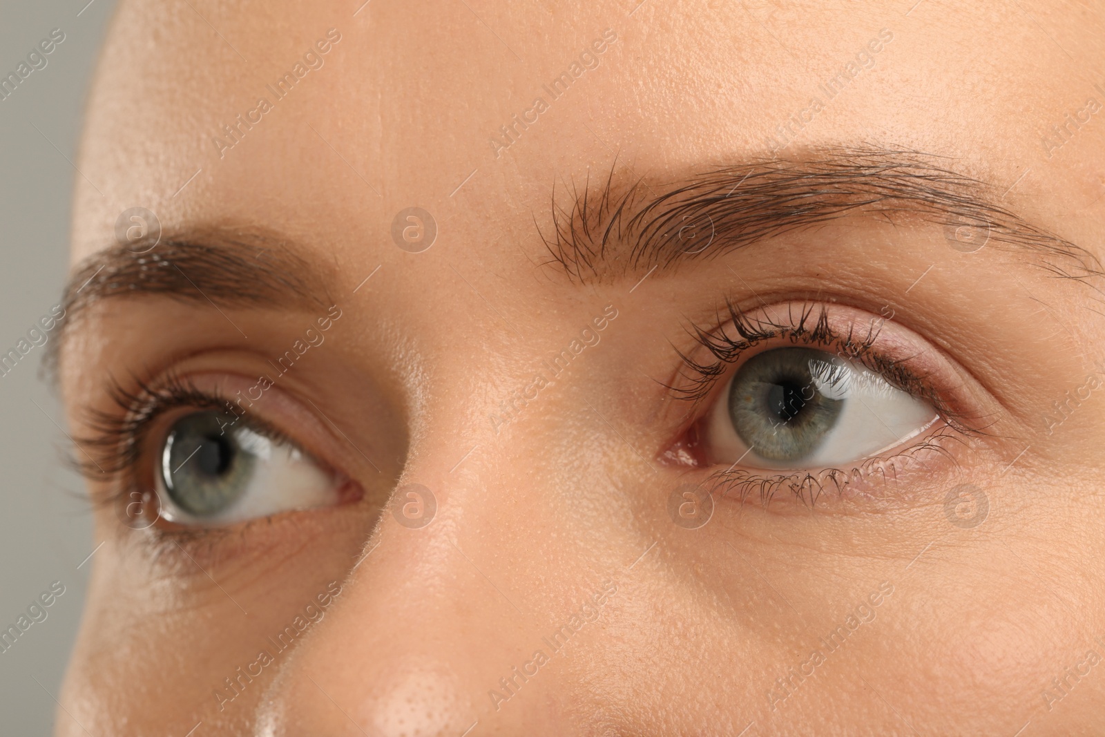 Photo of Woman with beautiful natural eyelashes on grey background, closeup