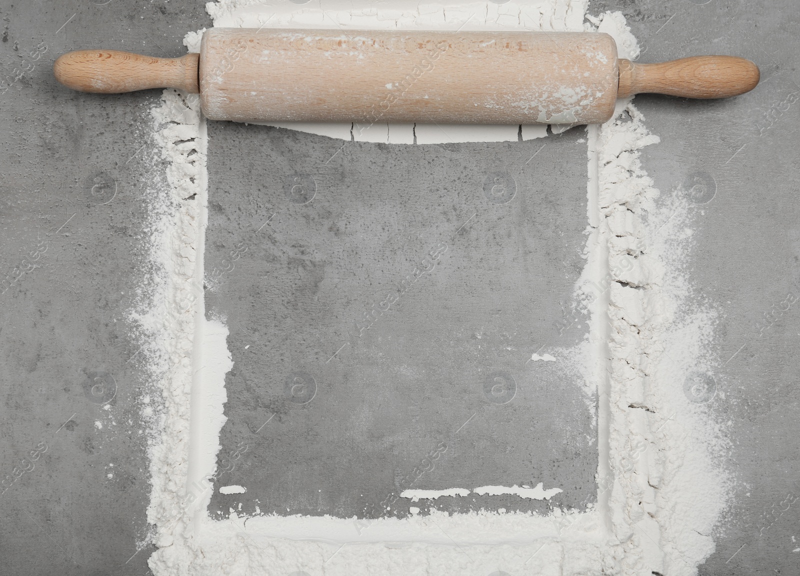 Photo of Flour and rolling pin on light grey table, top view. Space for text