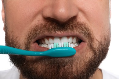 Man brushing teeth on white background, closeup. Dental care