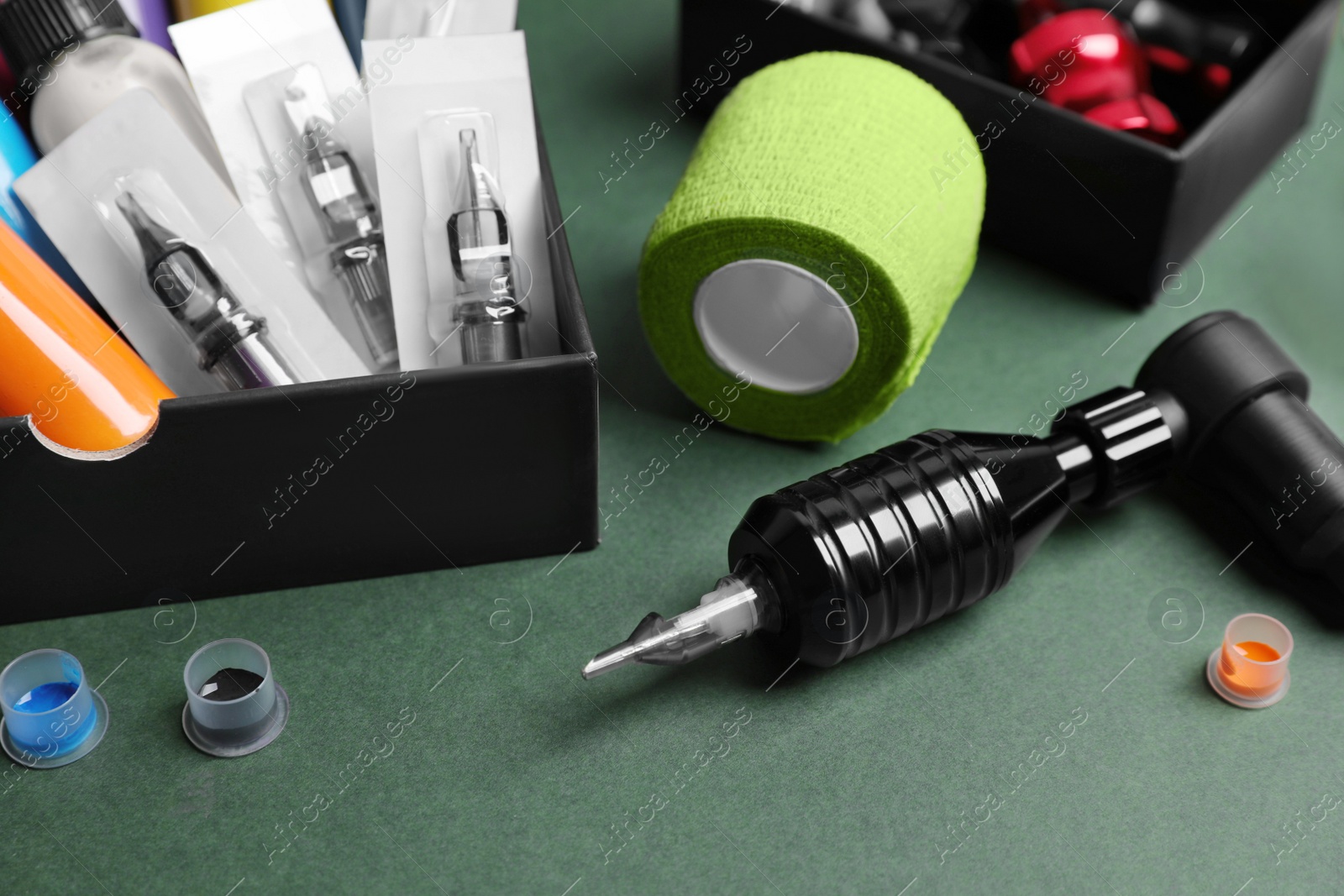 Photo of Tattoo equipment on dark green background, closeup