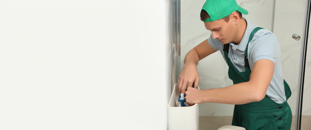 Image of Professional plumber repairing toilet tank in bathroom, space for text. Banner design