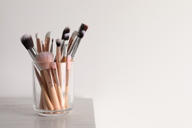 Photo of Set of professional brushes on wooden table against white background, space for text