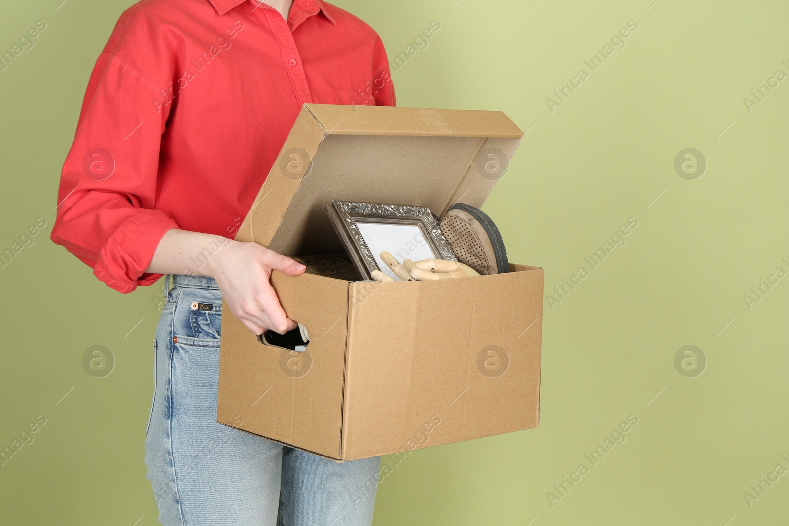 Photo of Woman holding box of unwanted stuff on green background, closeup