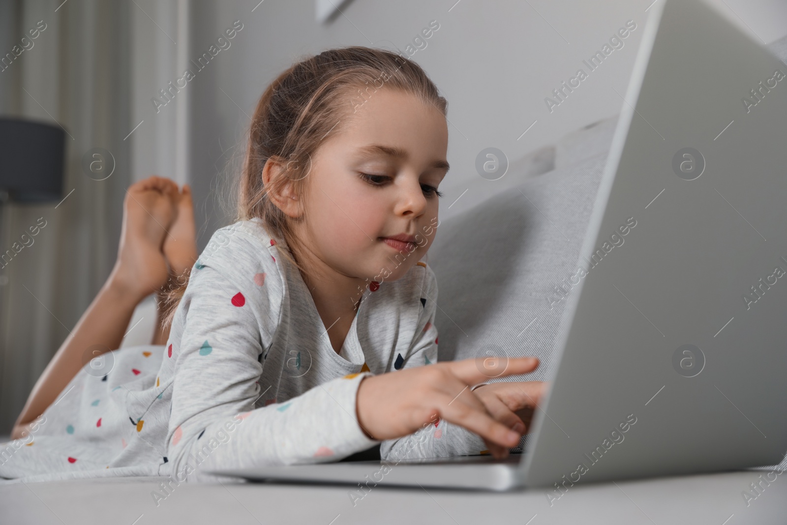 Photo of Little girl learning English indoors at online lesson