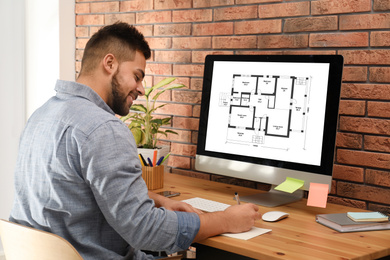 Image of Architect making project of house house on computer in office