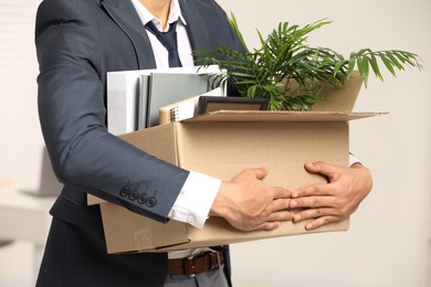 Photo of Unemployment problem. Man with box of personal belongings in office, closeup