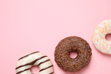 Photo of Delicious glazed donuts on pink background, flat lay. Space for text