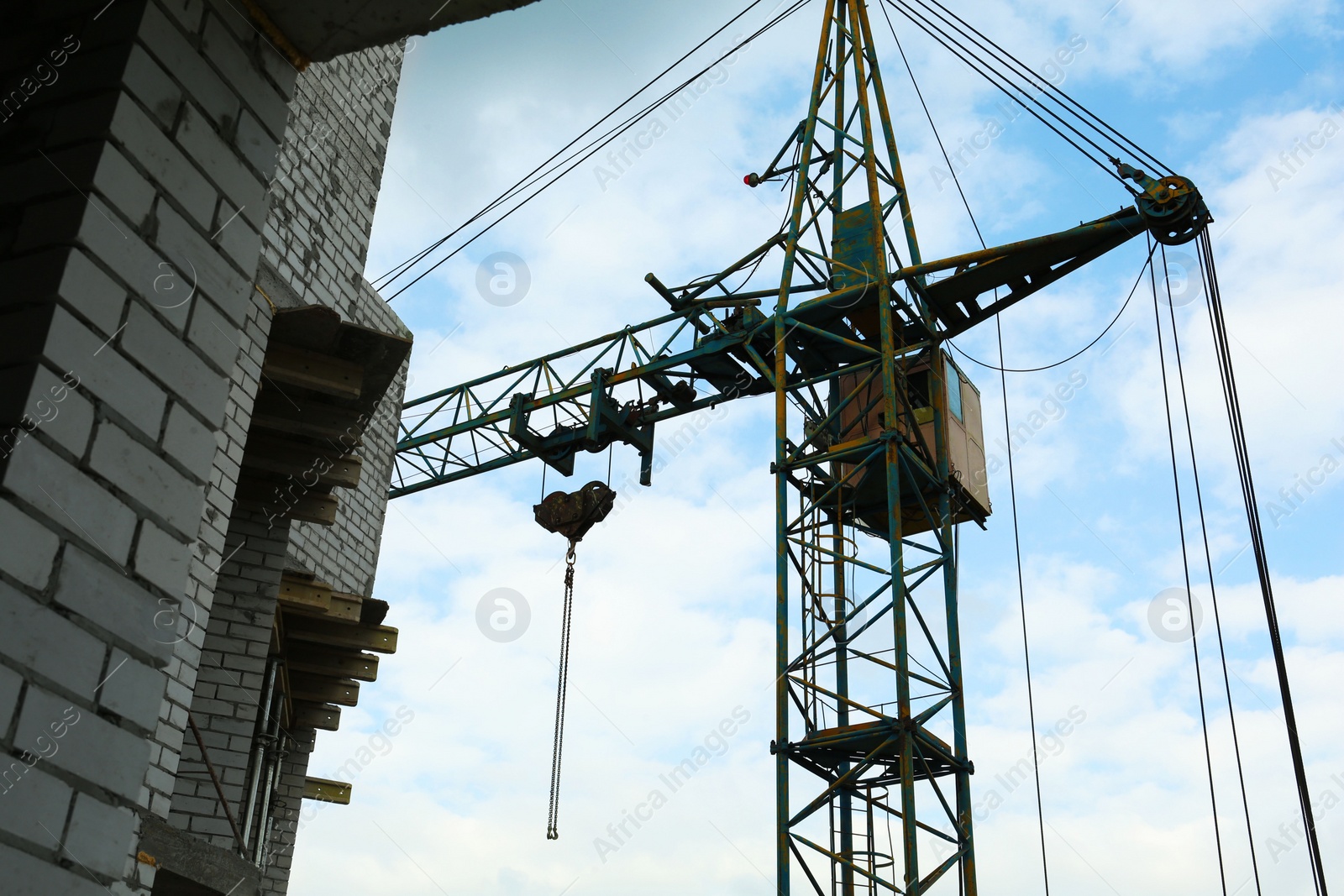 Photo of Construction site with tower crane under beautiful cloudy sky, low angle view