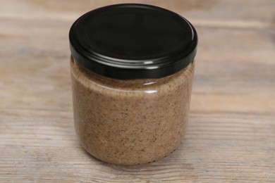 Tasty nut paste in jar on wooden table, closeup