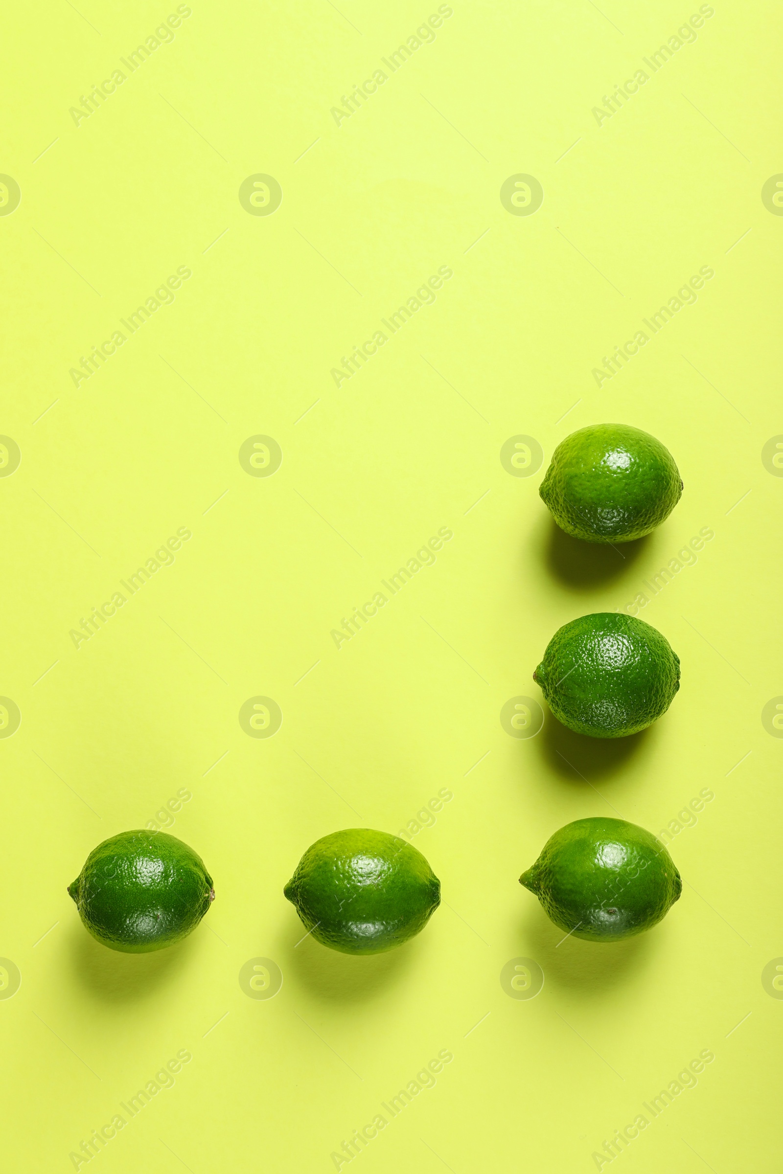 Photo of Flat lay composition with fresh juicy limes on yellow background, space for text