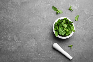 Photo of Fresh mint with mortar and pestle on grey background, flat lay. Space for text