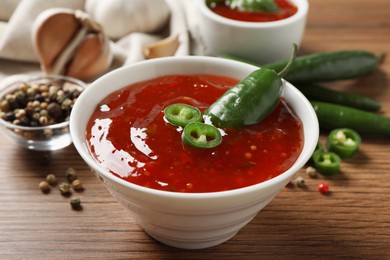 Photo of Spicy chili sauce in bowl on wooden table