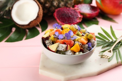 Photo of Delicious exotic fruit salad served on pink wooden table