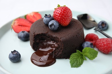 Photo of Delicious chocolate fondant, berries and mint on plate, closeup