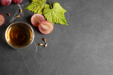 Photo of Bowl of natural grape seed oil on dark table, flat lay with space for text. Organic cosmetic