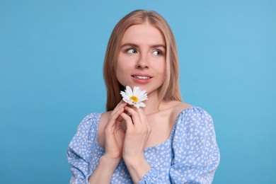 Beautiful woman with spring flower in hands on light blue background