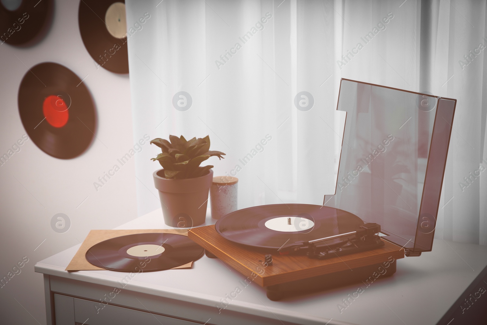 Image of Stylish turntable on white chest of drawers and vinyl records indoors