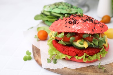 Photo of Tasty pink vegan burger with vegetables, patty and microgreens on white tiled table, closeup. Space for text