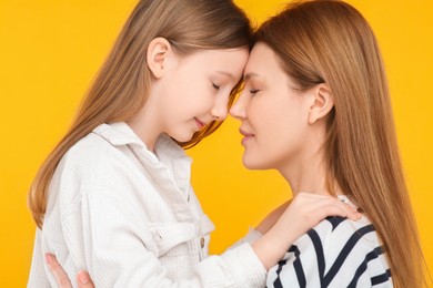 Portrait of mother and her cute daughter on orange background