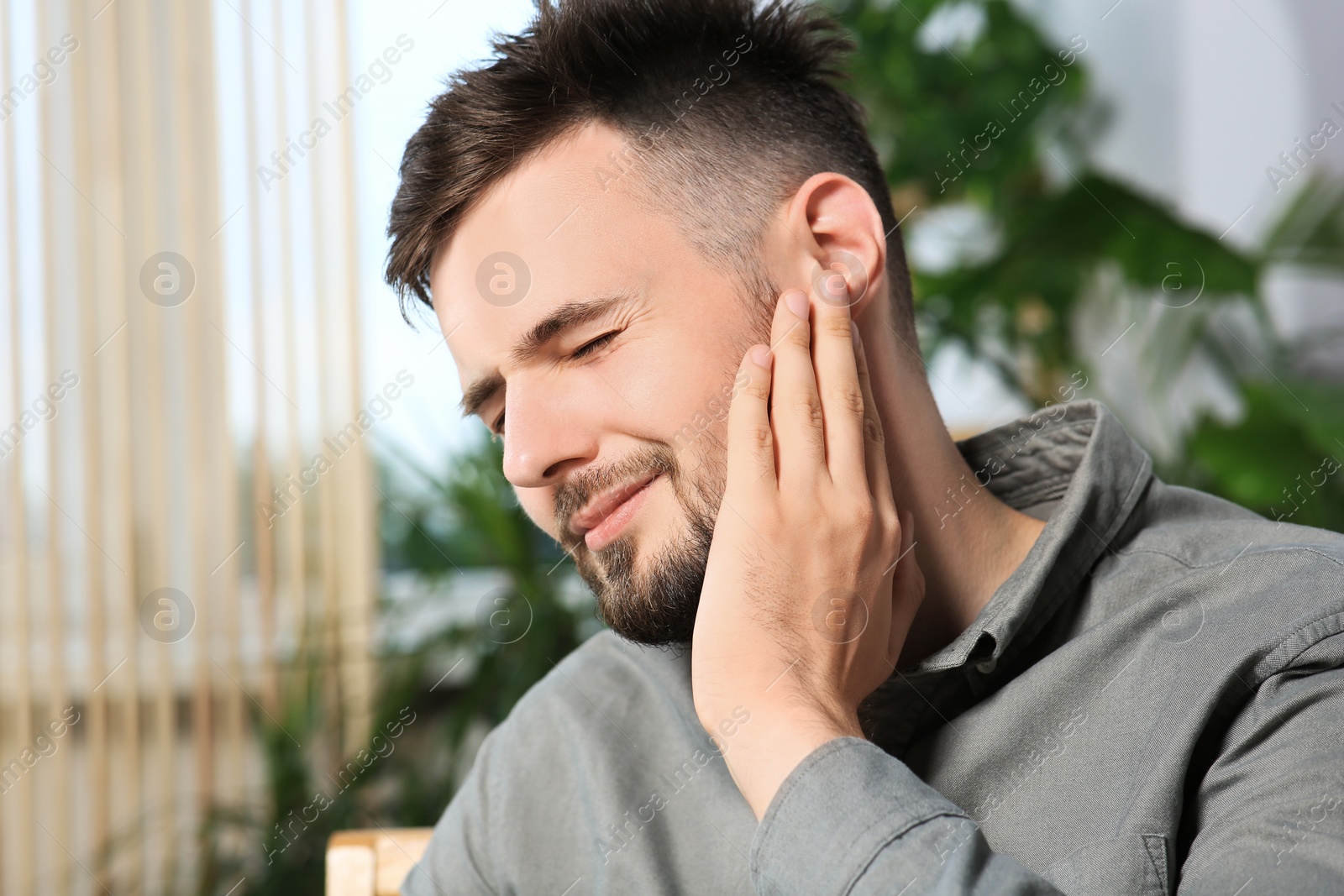 Photo of Young man suffering from ear pain at home
