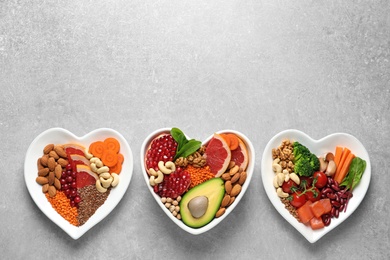 Photo of Plates with heart-healthy diet products on grey background, top view. Space for text