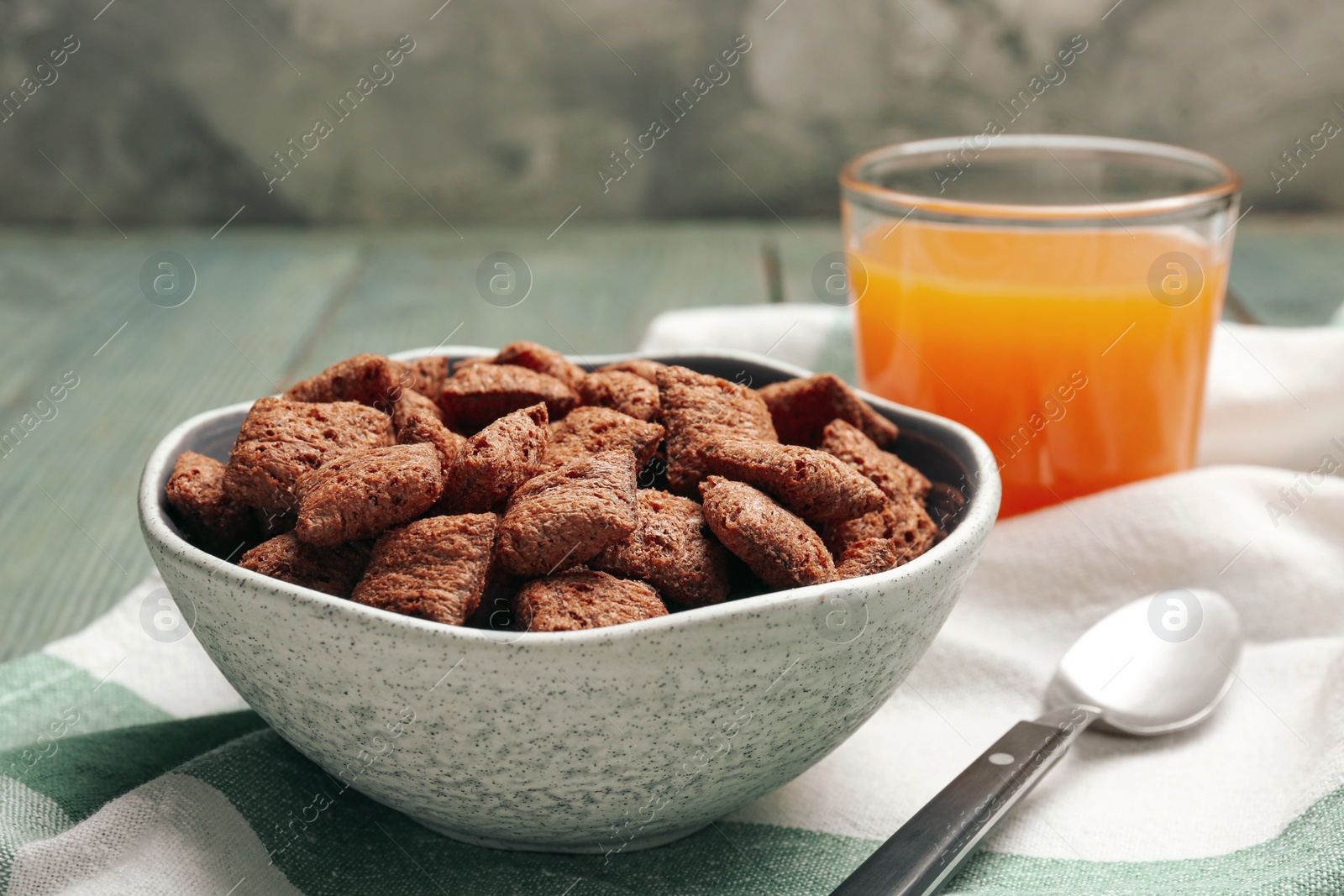 Photo of Bowl of sweet crispy corn pads and juice on blue wooden table. Breakfast cereal