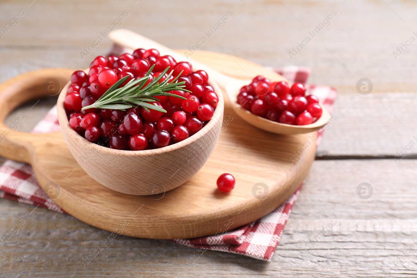 Photo of Fresh ripe cranberries and rosemary on wooden table