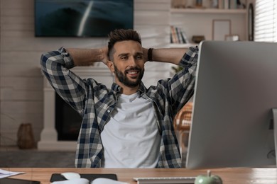 Photo of Man relaxing near computer at workplace in home office