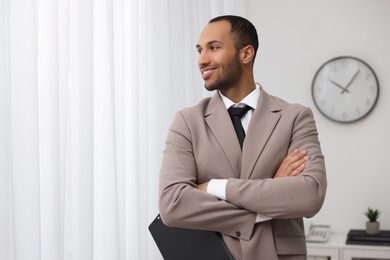 Photo of Portrait of smiling young man with clipboard in office, space for text. Lawyer, businessman, accountant or manager