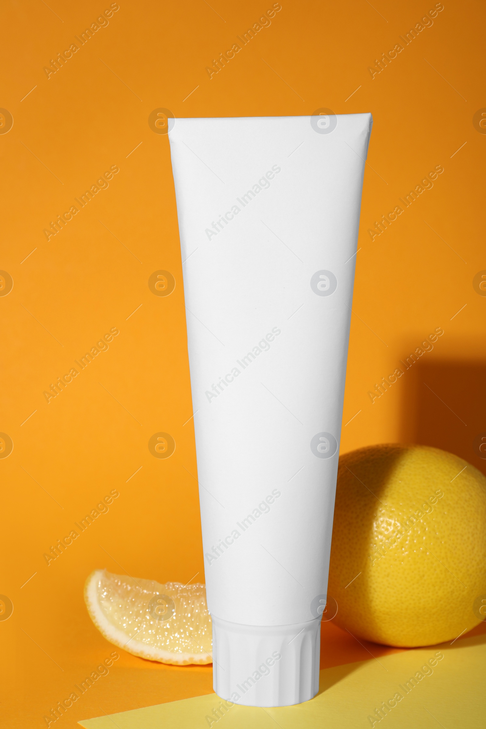 Photo of Blank tube of toothpaste and fresh lemon on color background