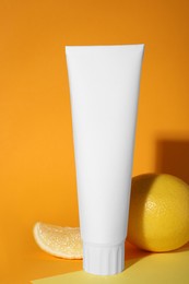 Photo of Blank tube of toothpaste and fresh lemon on color background