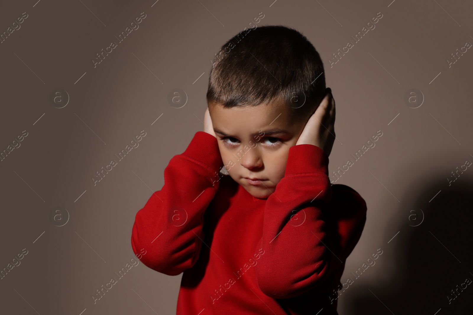 Photo of Scared little boy on beige background. Domestic violence concept