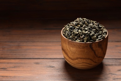 Photo of Bowl of Tie Guan Yin oolong tea leaves on wooden table. Space for text